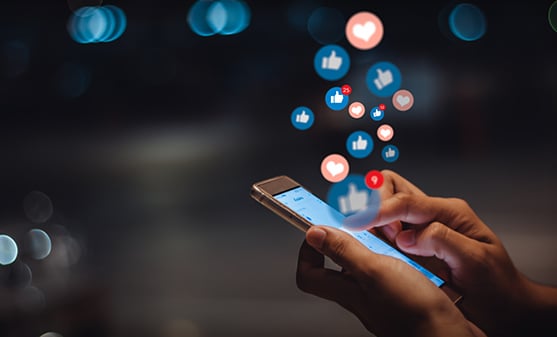 Holding mobile phone with social media emojis