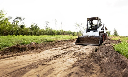 A skid steer working in a field A skid steer working in a field